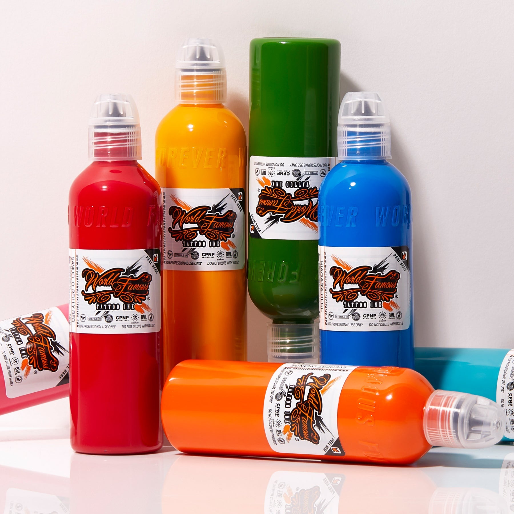A bright cluster of World Famous Tattoo Ink bottles showing off bold red, orange, green, and blue colors.