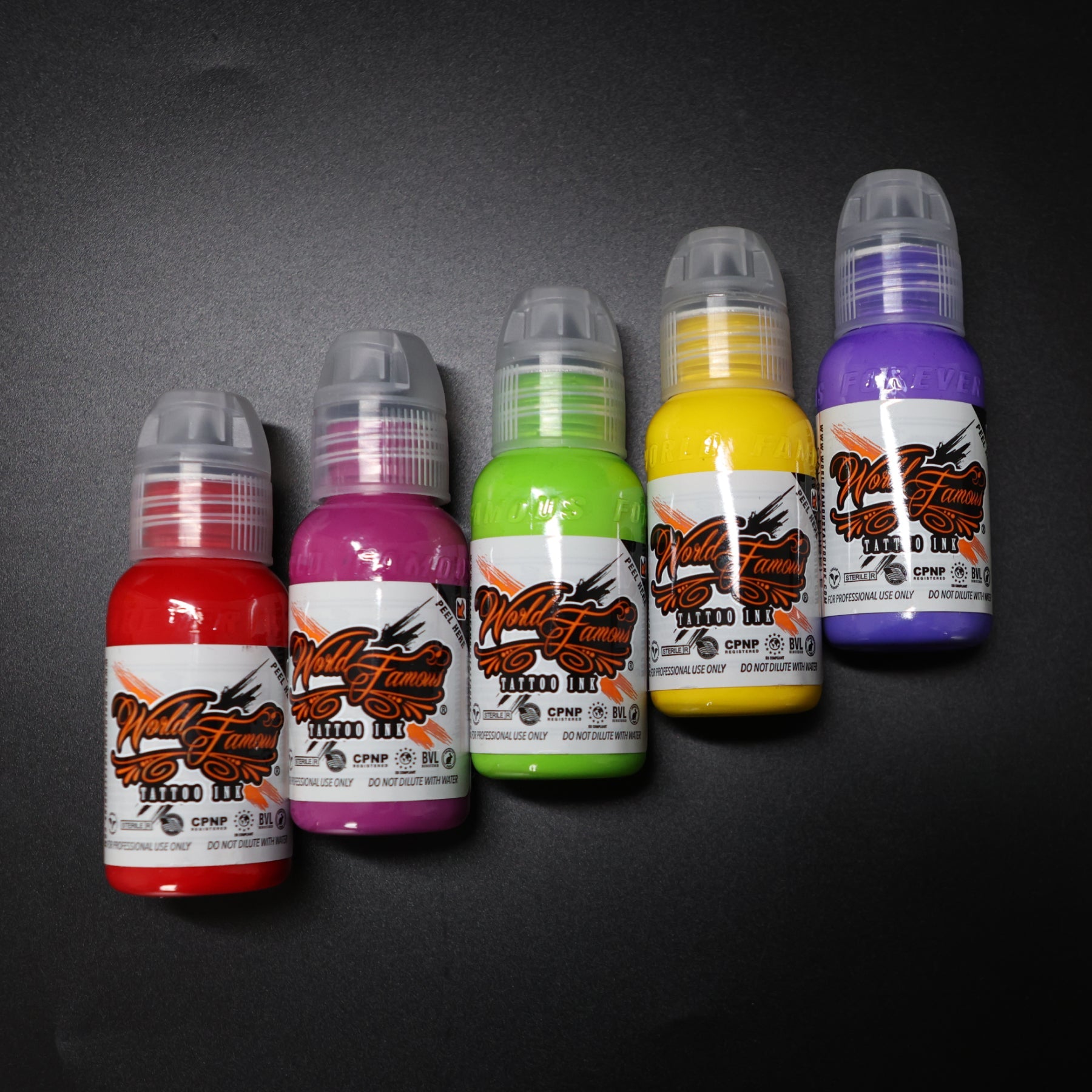 A sequential row of five colorful tattoo ink bottles arranged for testing custom additive ratios and color-enhancing drops.