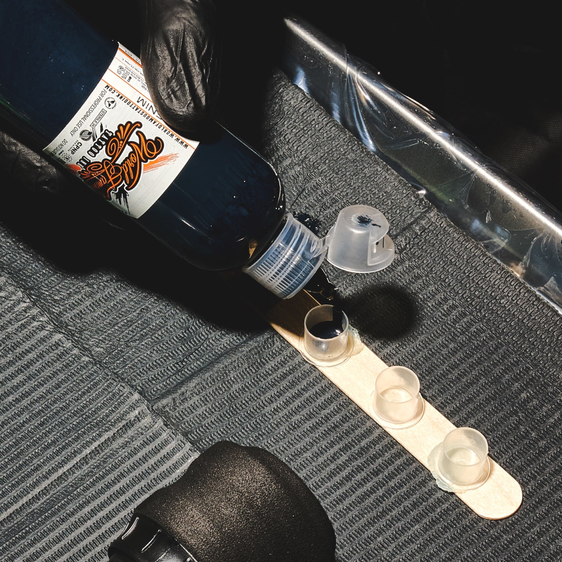 Black tattoo ink being poured into an ink cap.